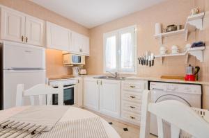 a kitchen with white appliances and a table and chairs at Villas Vanessa & Ruth in Cala en Porter
