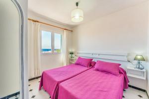 a bedroom with a pink bed with a window at Villas Vanessa & Ruth in Cala en Porter +16 photos