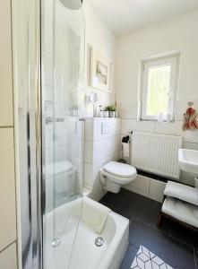 a white bathroom with a shower and a toilet at Ferienwohnung am Olantis in Oldenburg +16 photos