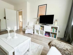 a living room with a tv and a white table at Ferienwohnung am Olantis in Oldenburg