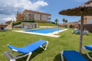 a resort with a swimming pool and two blue chairs and an umbrella at Casa Patagonia in Manilva