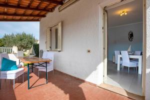 a patio with a wooden table and white chairs at Villetta I Pitosfori in Palmadula +12 photos