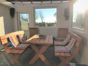 a wooden table and chairs in a room with windows at Haus Sonnenschein in Janneby