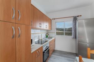 a kitchen with wooden cabinets and a stainless steel refrigerator at Los Adejo vacacional in Moya