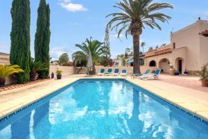 a swimming pool with palm trees and lounge chairs at Villa Shalimar Moraira in Teulada