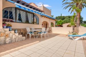 a patio with a table and chairs in front of a house at Villa Shalimar Moraira in Teulada