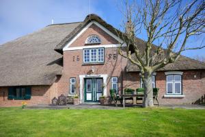 a brick house with a tree in front of it at Knutzenswarft - Deichgraf in Westerhever