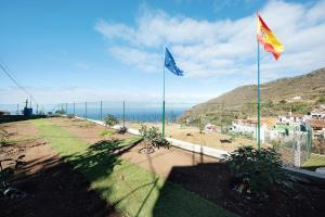 two flags on a hill with the ocean in the background at El Lagar in Los Silos