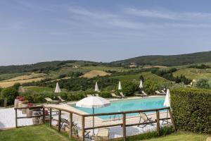 a pool with chairs and umbrellas and a view of a mountain at Suite Fattoressa in San Gimignano