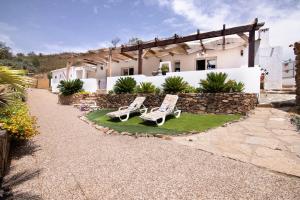 a patio with two lawn chairs and a stone wall at Quinta do Silêncio T4 in Tavira