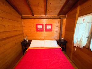 a bed in a wooden room with two tables at Le sorgenti - Chalet 57 in Palazzuolo sul Senio