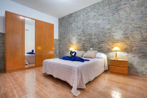 a bedroom with a bed and a stone wall at Casa Dayaday in Puerto del Rosario