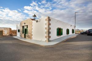 a white building with green windows on a street at Casa Dayaday in Puerto del Rosario