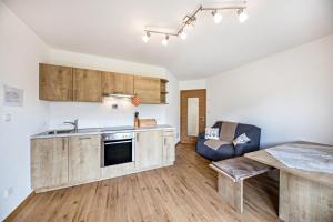 a kitchen with wooden cabinets and a table and a couch at Tschafon Oberparnaihof in Collepietra
