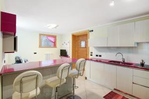 a kitchen with white cabinets and pink counter tops at Tea da Anna e Luigi in Livigno