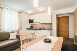 a kitchen and living room with a table and a couch at Chalet La Flüta Primula in La Valle