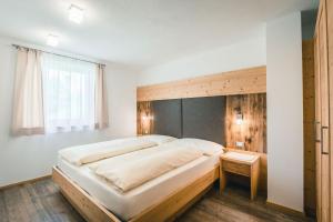 a bedroom with a large bed with a wooden headboard at Chalet La Flüta Primula in La Valle