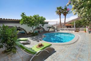 a swimming pool with chaise lounge chairs next to a house at Finca Fani 2 in Agüimes
