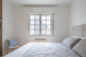 a white bedroom with a bed and a window at Casita Do Muelle - Cambados in Cambados