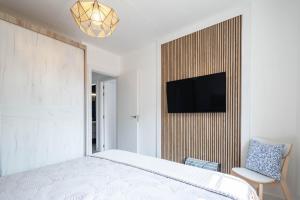 a bedroom with a bed and a tv on a wall at Casita Do Muelle - Cambados in Cambados
