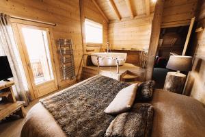 a bedroom with a bed and a tub in a cabin at Chalet Bachal in Manigod