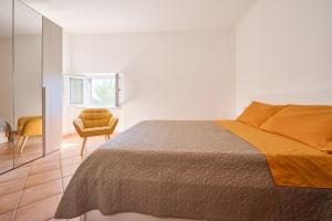 a white bedroom with a bed and a chair at La Casa Di Simba A Piombino in Piombino