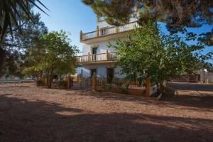 a large white building with a fence and trees at Villa Los Pinos in Marchena