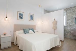 a white bedroom with a white bed with blue pillows at Villa Sandra solo familias in Cádiz +15 photos