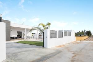 a white house with a palm tree in the driveway at Villa Sandra solo familias in Cádiz