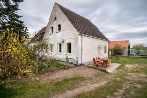 an old white house with a table and chairs at Landglück in Hohenmocker