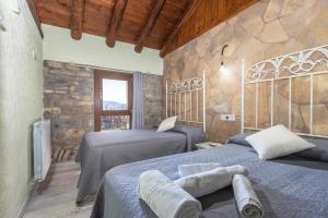 a bedroom with two beds and a stone wall at Casa Perico in Borrastre