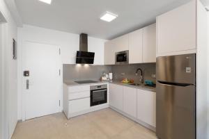 a kitchen with white cabinets and a stainless steel refrigerator at Ocean wave retreat in Patalavaca