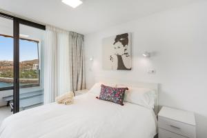 a bedroom with a white bed with a window at Ocean wave retreat in Patalavaca
