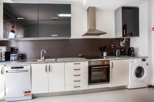 a kitchen with white cabinets and a washer and dryer at Apartment Beach Waves Home in Nazaré