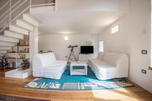 a living room with two white chairs and a television at Villa Iagra in Tiarno di Sopra