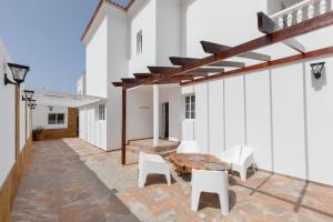 a patio with a wooden table and white chairs at La Villa in Tarajalejo