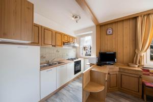 a kitchen with wooden cabinets and a tv on a counter at Appartamento Primavera 1 in Moena