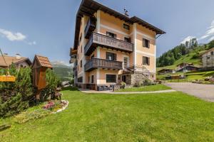 a building with a grassy yard in front of it at Appartamento Primavera 1 in Moena