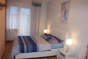 a bedroom with a bed with two lamps and a window at Apartament Rajska in Gdańsk