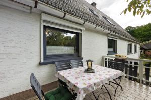 a table and chairs sitting on a deck with a window at Fewo Schober in Kirchhundem