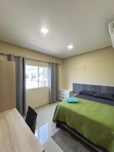 a bedroom with a green bed and a window at Flat 2 Suítes, piscina e churrasqueira em Alter in Alter do Chao +27 photos