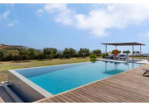 a swimming pool with a wooden deck next to a house at Luna Rossa Milos - Olive Home in Provatas