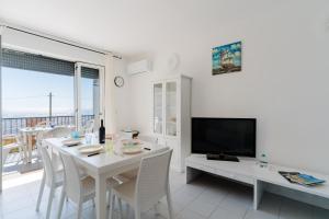 a white dining room with a table and a tv at Olimpia's home in Otranto in Otranto
