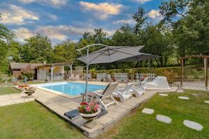 a swimming pool with chairs and an umbrella next to a pool at La Villa du Mas des Chenes in Pomport