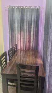 a dining room table with chairs and a wooden table and curtains at Tungnath View Homestay in Sari