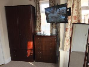 a living room with a dresser and a flat screen tv at The Monsell Hotel in Skegness