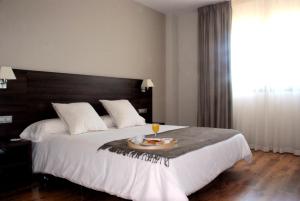 a bedroom with a large bed with a tray of food on it at Hotel Pago del Olivo in Simancas