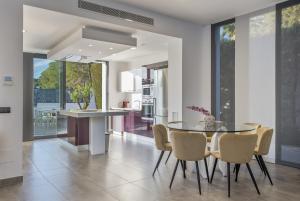 a kitchen and dining room with a glass table and chairs at Villa Elite Maribiza in Cala Llena