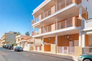 a building with balconies and cars parked on a street at Playa de Chilches in Chilches