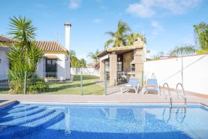 a swimming pool with two chairs and a house at Casa Villanueva 2 - Sólo Familias in Conil de la Frontera